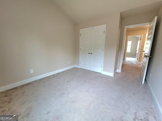unfurnished bedroom with baseboards, vaulted ceiling, carpet flooring, and a closet