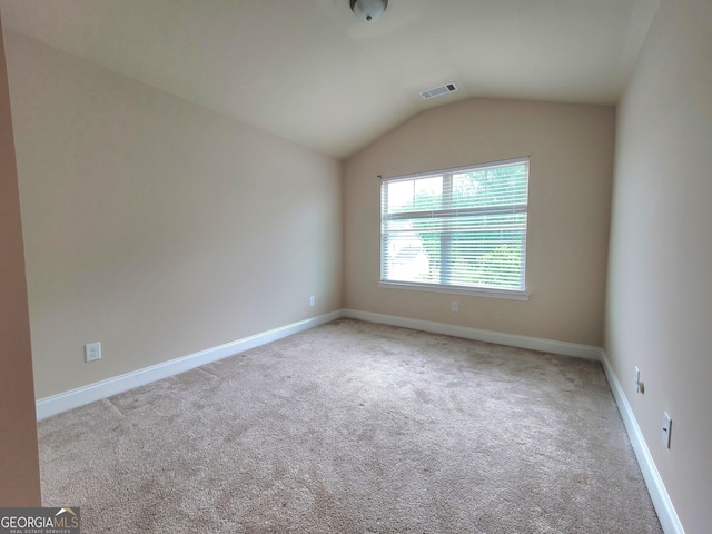 carpeted empty room with lofted ceiling, visible vents, and baseboards