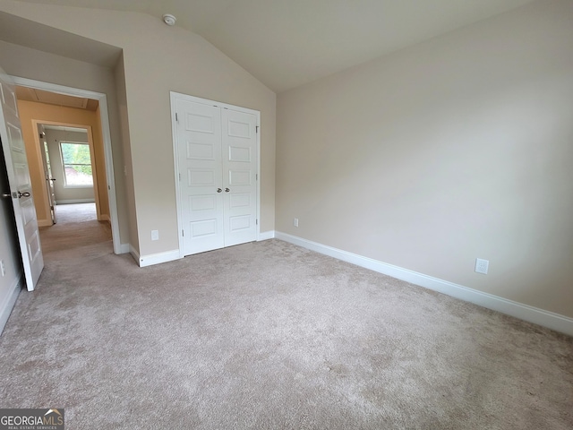 unfurnished bedroom featuring attic access, baseboards, carpet flooring, and vaulted ceiling