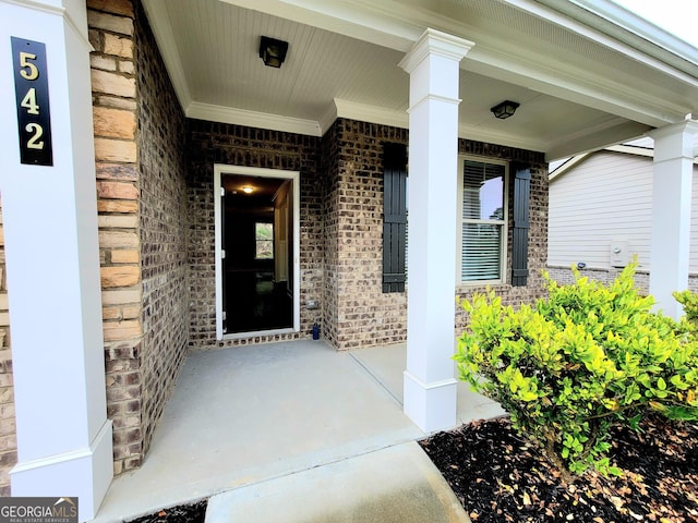 entrance to property with brick siding and a porch