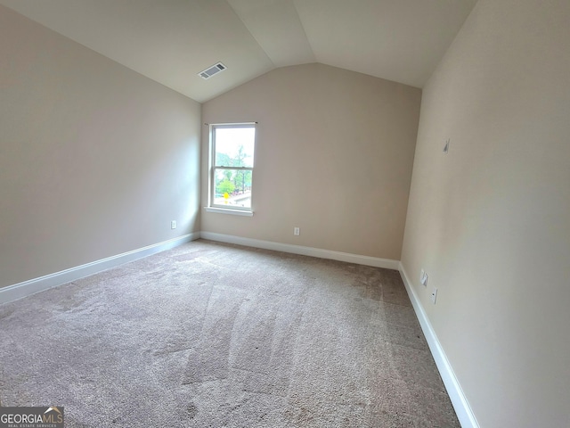 spare room featuring lofted ceiling, carpet floors, visible vents, and baseboards