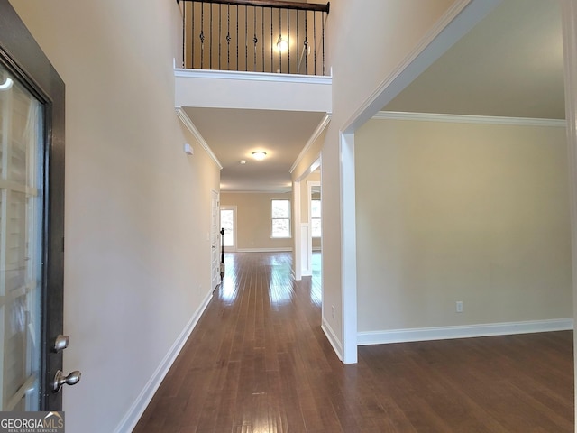 foyer entrance with wood-type flooring, baseboards, and crown molding
