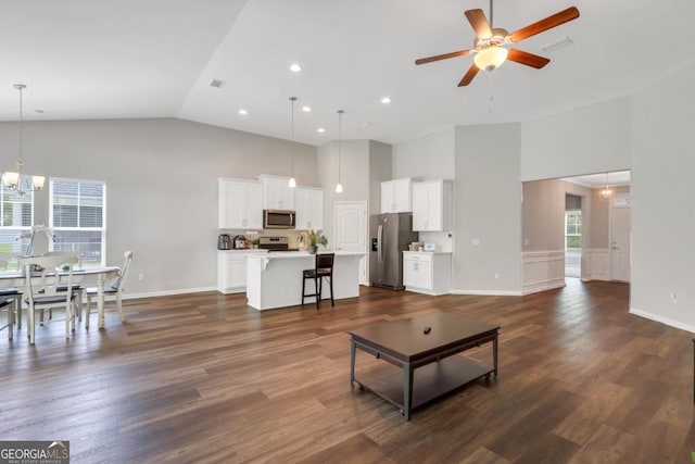 128 Clearwater Dr, Brunswick, GA 31523 - living area featuring ceiling fan with notable chandelier, baseboards, high vaulted ceiling, and dark wood-style flooring