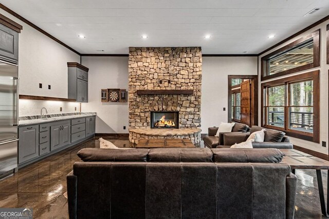 living area featuring baseboards, a stone fireplace, recessed lighting, and crown molding