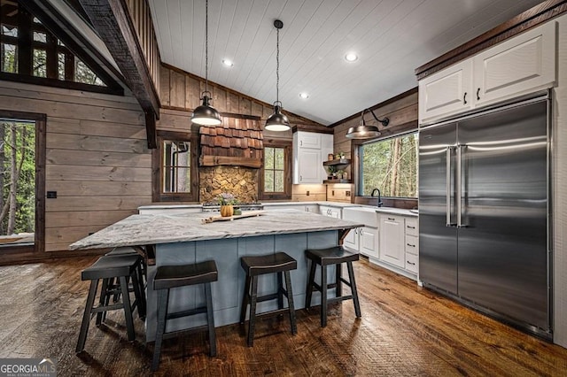 kitchen with stainless steel built in refrigerator, a wealth of natural light, a sink, vaulted ceiling, and white cabinetry