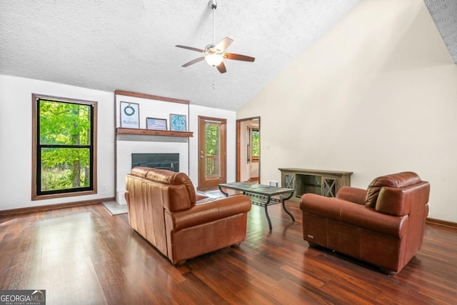 living room with a ceiling fan, wood finished floors, a fireplace, and a textured ceiling