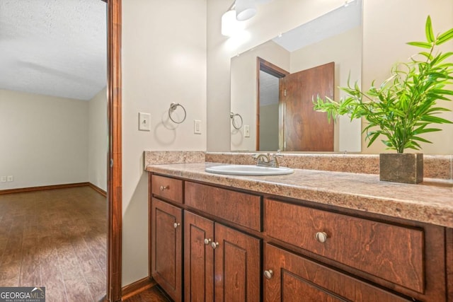 bathroom featuring baseboards, wood finished floors, and vanity