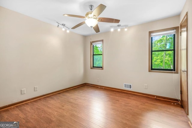 spare room with track lighting, visible vents, light wood-type flooring, baseboards, and ceiling fan