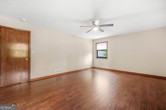 empty room featuring wood finished floors, visible vents, a ceiling fan, and baseboards