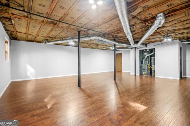 finished below grade area with water heater, baseboards, and wood-type flooring