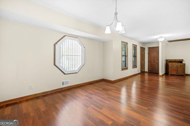 unfurnished living room with visible vents, baseboards, wood finished floors, and a chandelier