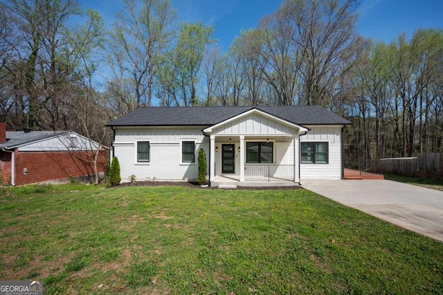 ranch-style house with a front lawn, driveway, board and batten siding, fence, and a porch