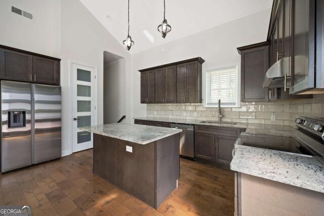 kitchen with stainless steel appliances, a sink, visible vents, dark brown cabinetry, and exhaust hood