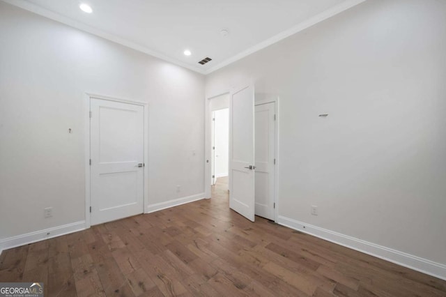 unfurnished bedroom with crown molding, wood finished floors, baseboards, visible vents, and recessed lighting