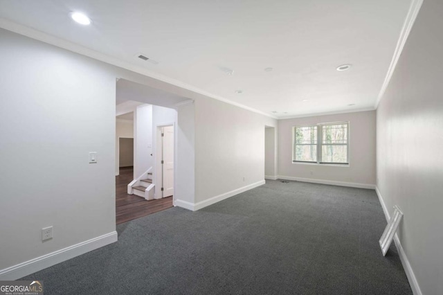 empty room featuring baseboards, visible vents, dark carpet, and crown molding