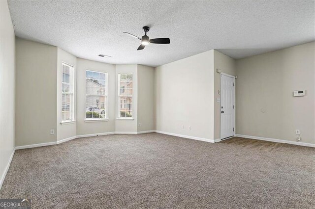 carpeted empty room with visible vents, baseboards, a textured ceiling, and ceiling fan