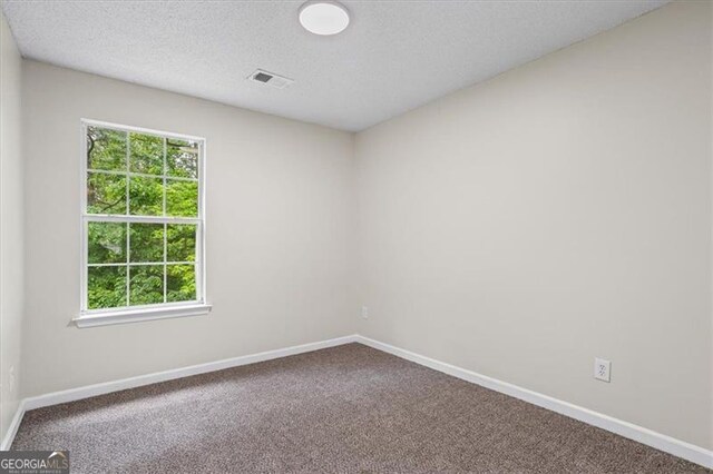 spare room featuring visible vents, carpet flooring, and baseboards