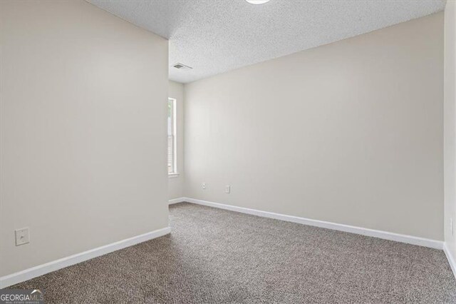 carpeted empty room with baseboards, visible vents, and a textured ceiling