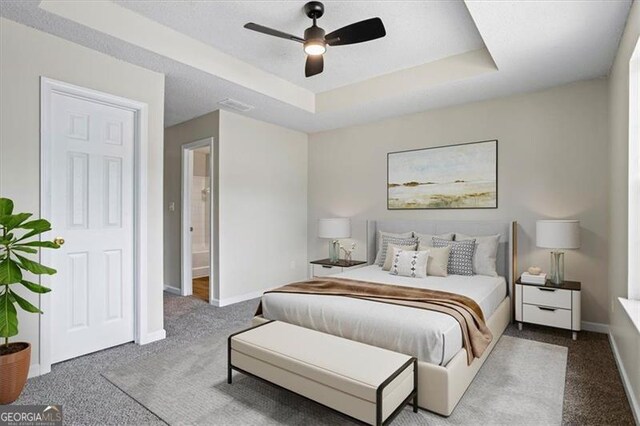 carpeted bedroom with a ceiling fan, baseboards, and a raised ceiling