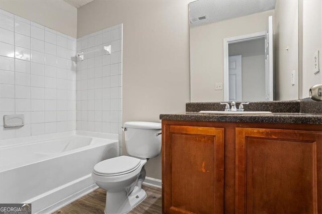 full bathroom featuring toilet, shower / bathing tub combination, visible vents, wood finished floors, and vanity