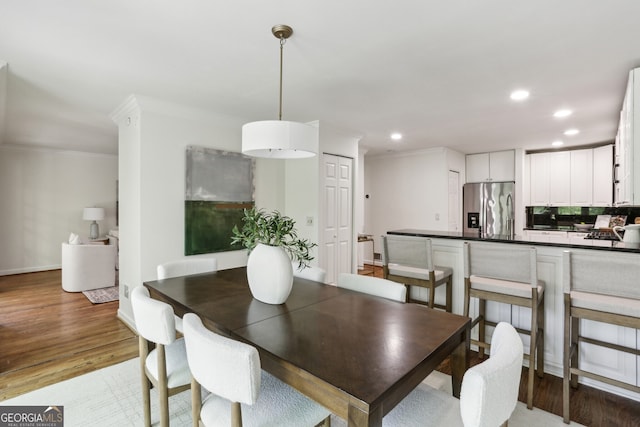 dining area with baseboards, ornamental molding, light wood-style floors, and recessed lighting