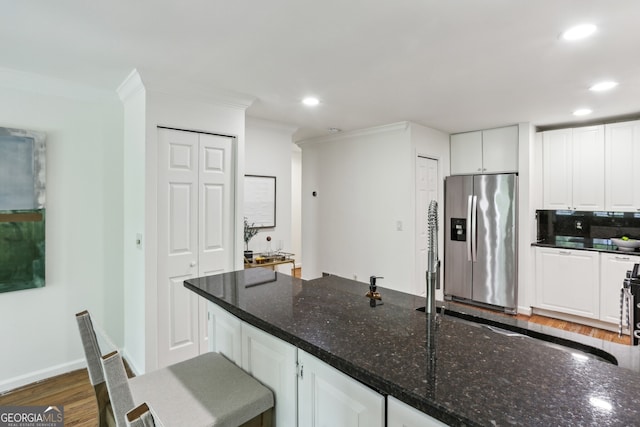 kitchen featuring stainless steel refrigerator with ice dispenser, crown molding, dark wood-type flooring, and recessed lighting