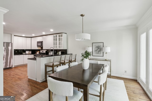 dining room with recessed lighting, light wood finished floors, baseboards, and ornamental molding