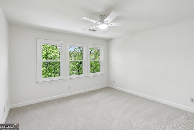 spare room with visible vents, a ceiling fan, baseboards, and light colored carpet