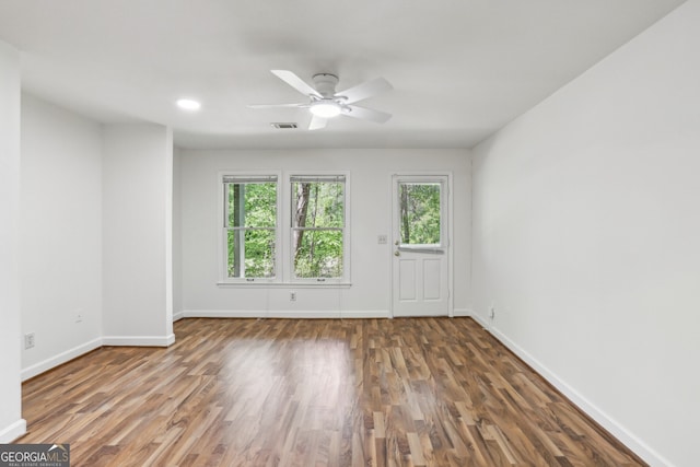 unfurnished room with baseboards, wood finished floors, visible vents, and a ceiling fan