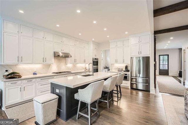 1059 Antioch Dr, Brookhaven, GA 30319 - kitchen featuring white cabinetry, under cabinet range hood, a sink, appliances with stainless steel finishes, and backsplash