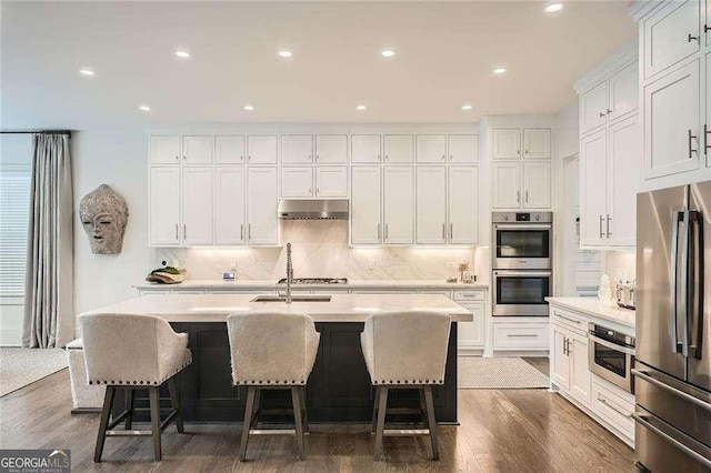 1059 Antioch Dr, Brookhaven, GA 30319 - kitchen featuring appliances with stainless steel finishes, a kitchen island with sink, under cabinet range hood, and white cabinetry