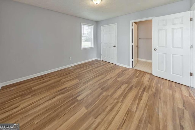 unfurnished bedroom featuring baseboards, light wood-style floors, and a closet
