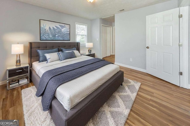 bedroom with baseboards, wood finished floors, and visible vents