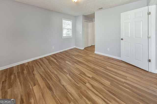 unfurnished bedroom with light wood finished floors, baseboards, and visible vents