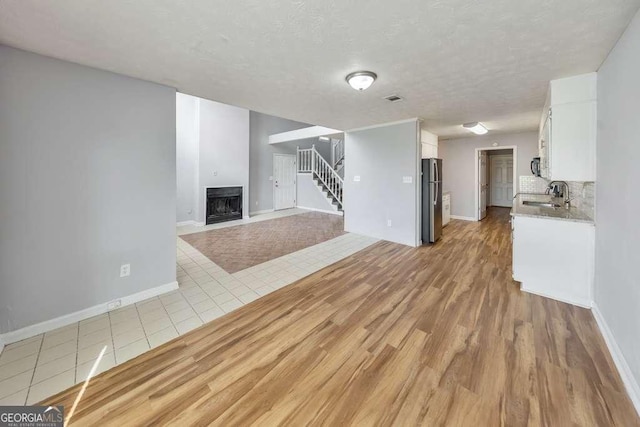 unfurnished living room featuring baseboards, a sink, and stairs