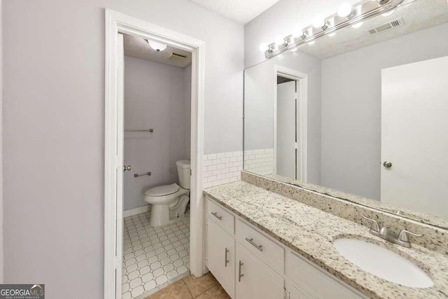 bathroom with tile patterned flooring, toilet, vanity, and visible vents
