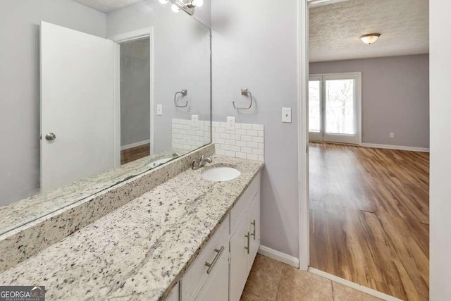 bathroom with wood finished floors, baseboards, vanity, and a textured ceiling