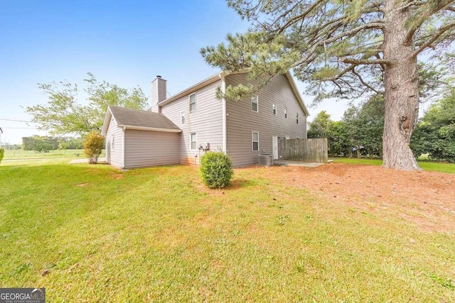 view of side of property featuring a lawn, a chimney, and central AC unit