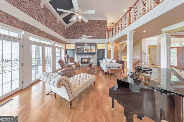 988 Hunters Rdg, Jasper, GA 30143 - living room with high vaulted ceiling, a stone fireplace, a ceiling fan, light wood-type flooring, and ornate columns