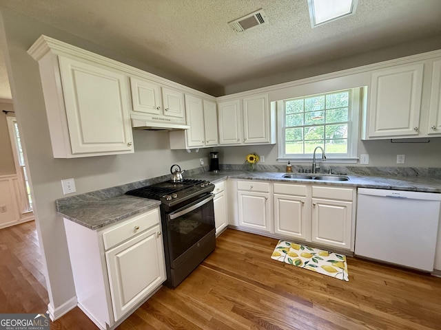 1087 Forsyth Landing Dr, Forsyth, GA 31029 - kitchen with gas stove, white dishwasher, under cabinet range hood, wood finished floors, and a textured ceiling
