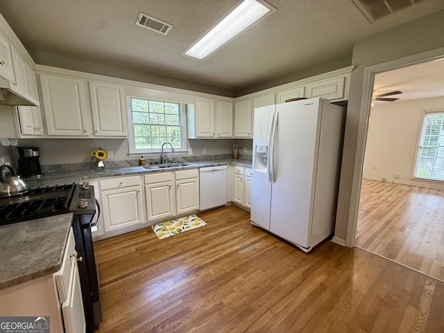 1087 Forsyth Landing Dr, Forsyth, GA 31029 - kitchen featuring white appliances, light wood-style flooring, white cabinets, healthy amount of natural light, and a textured ceiling