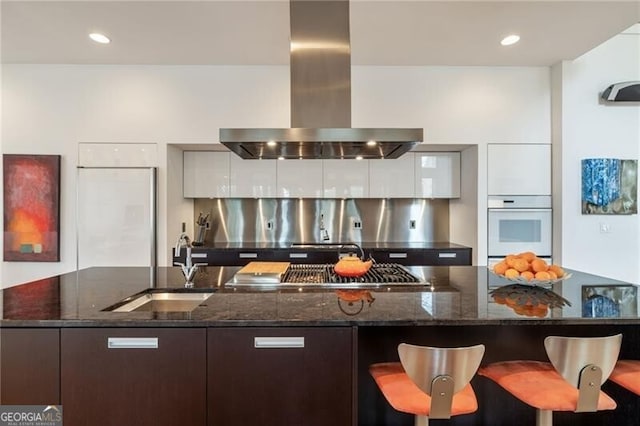 4835 Merlendale Ct, Atlanta, GA 30327 - kitchen featuring island exhaust hood, oven, a sink, modern cabinets, and stainless steel gas cooktop