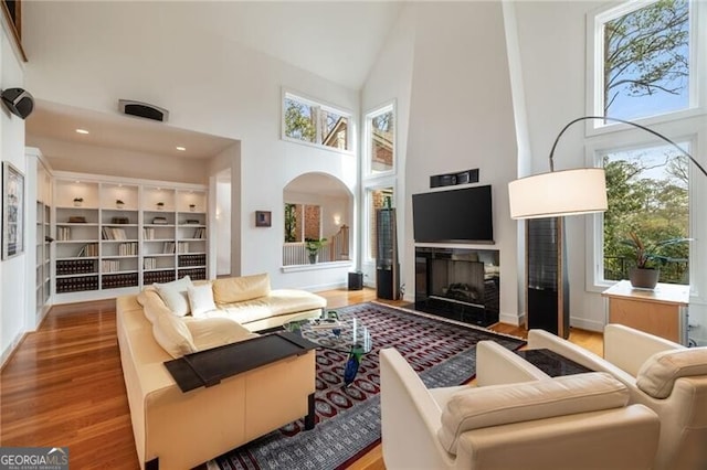4835 Merlendale Ct, Atlanta, GA 30327 - living room with a fireplace, wood finished floors, a high ceiling, and arched walkways
