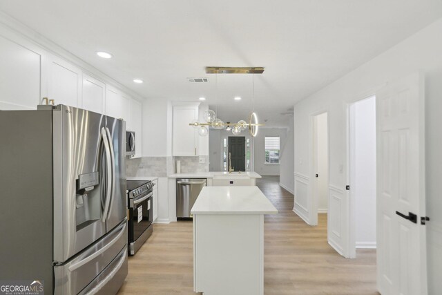 unfurnished living room featuring light wood-type flooring, baseboards, and ceiling fan with notable chandelier