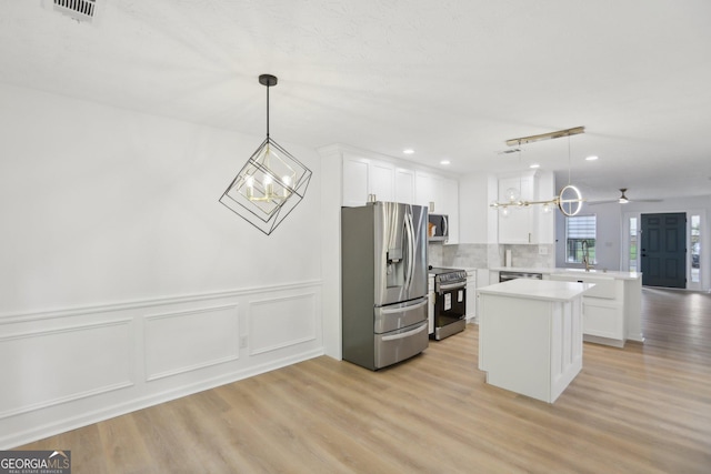 kitchen with a peninsula, white cabinetry, light countertops, a kitchen island, and appliances with stainless steel finishes