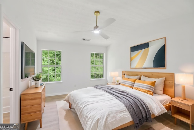 spare room with light wood-type flooring, a ceiling fan, visible vents, and a healthy amount of sunlight