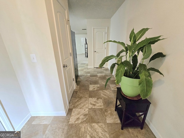 hallway with baseboards and light stone finish flooring