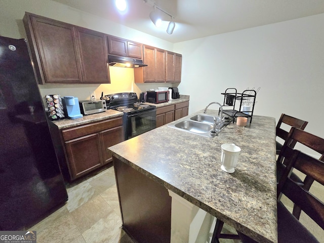 kitchen with black appliances, a sink, under cabinet range hood, and track lighting