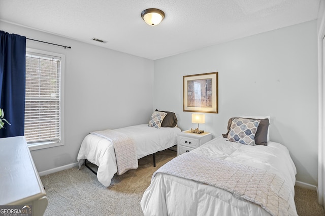 bedroom featuring carpet floors, a textured ceiling, baseboards, and visible vents