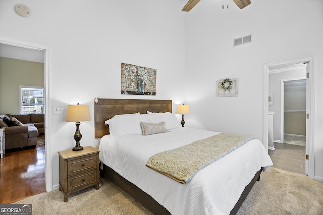 bedroom with ceiling fan, baseboards, ensuite bathroom, a towering ceiling, and visible vents
